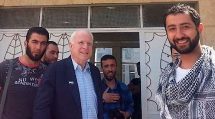 John McCain durante su estancia ilegal en territorio sirio. En primer plano a la derecha aparece el director de la Syrian Emergency Task Force. Al centro de la imagen, parado en la puerta, aparece Mohammad Nur.